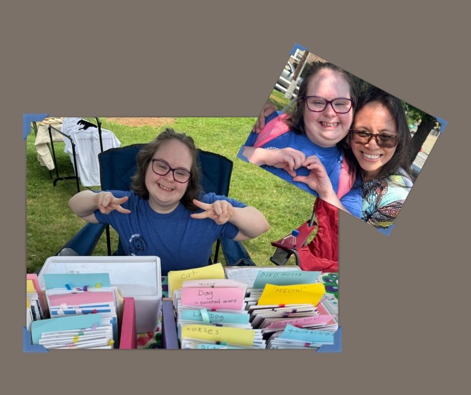 Amy smiles beside her handmade cards at a local market — a joyful moment of creative connection and shared artistry.